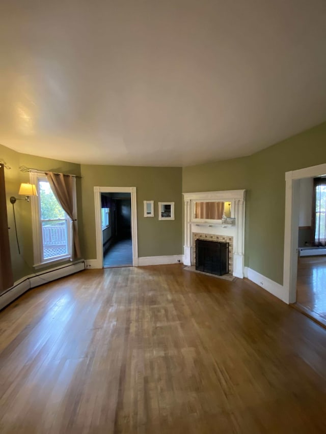 unfurnished living room with a fireplace, baseboards, a wealth of natural light, and wood finished floors