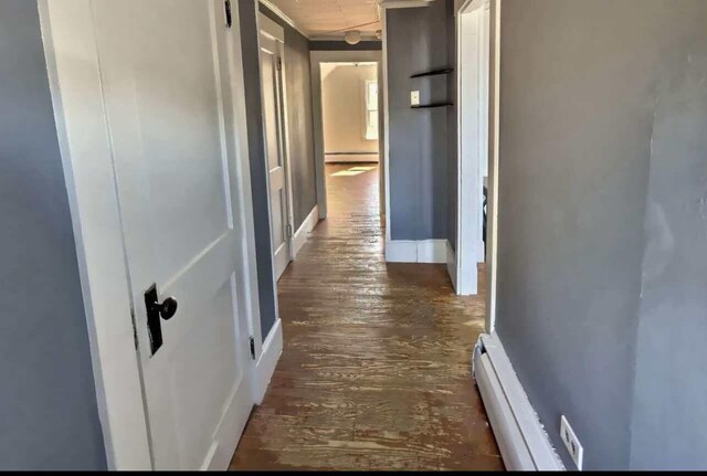 corridor featuring a baseboard heating unit and dark hardwood / wood-style floors