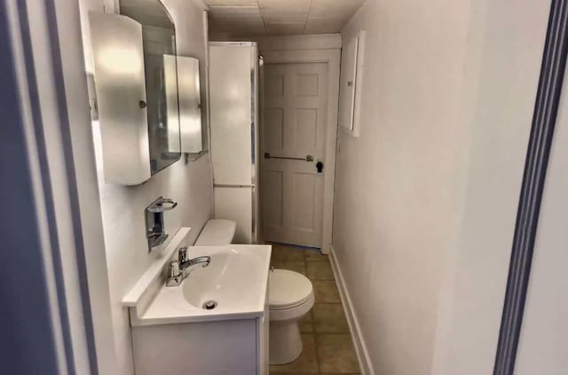 bathroom with baseboards, toilet, vanity, and tile patterned floors