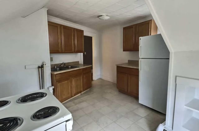 kitchen with white appliances, brown cabinetry, light countertops, and a sink