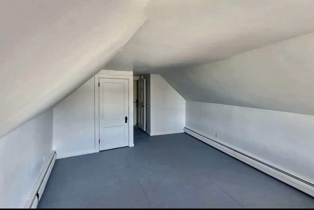 bonus room featuring a baseboard heating unit and lofted ceiling