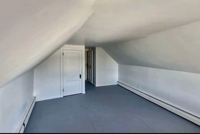 additional living space with a baseboard radiator, lofted ceiling, and concrete floors