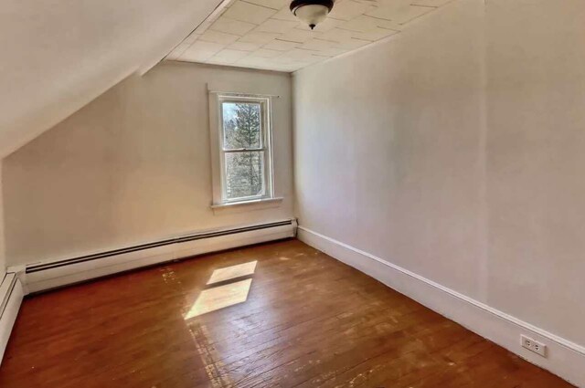 additional living space with a baseboard heating unit, dark hardwood / wood-style flooring, and vaulted ceiling