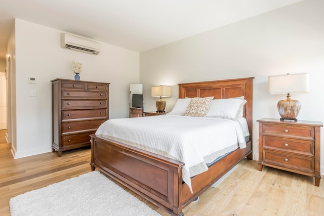 bedroom featuring light wood-type flooring and a wall mounted air conditioner