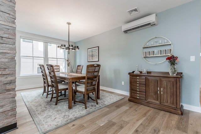 dining space featuring light hardwood / wood-style floors, a chandelier, and a wall mounted air conditioner