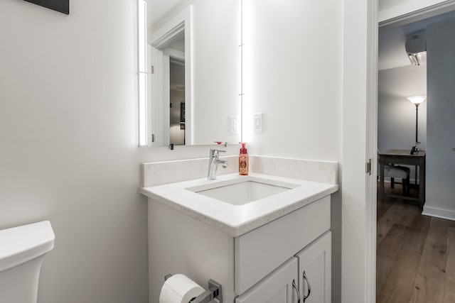 bathroom with wood-type flooring, vanity, and toilet