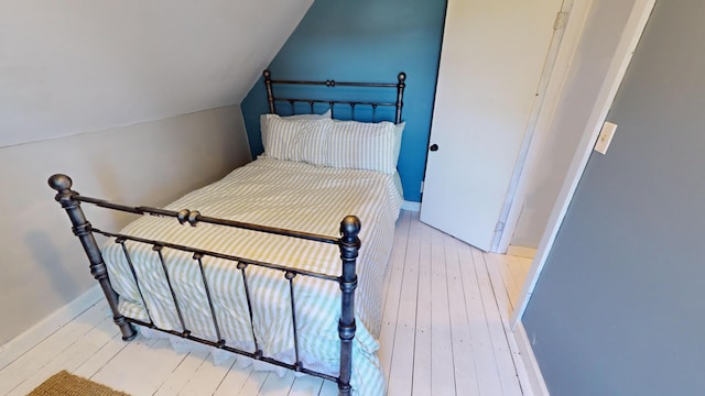 bedroom with light wood-type flooring and vaulted ceiling