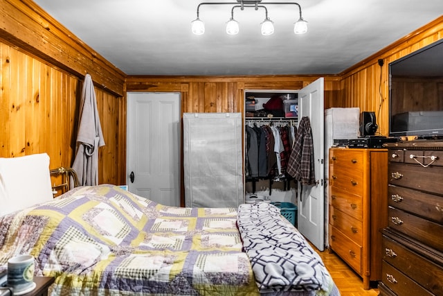 bedroom with stainless steel refrigerator, wooden walls, ornamental molding, light parquet flooring, and a closet