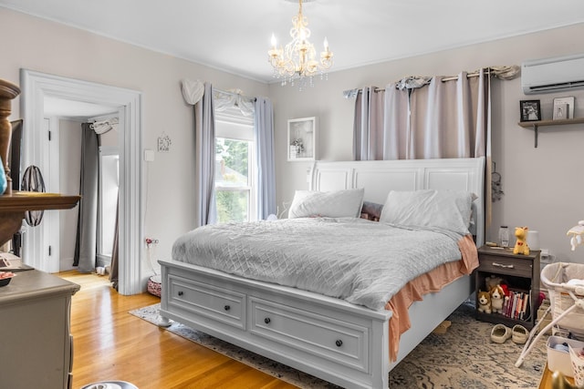 bedroom featuring a wall mounted air conditioner, a notable chandelier, and light wood-style floors