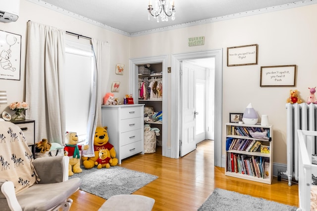recreation room featuring light wood-style floors, radiator heating unit, and an inviting chandelier