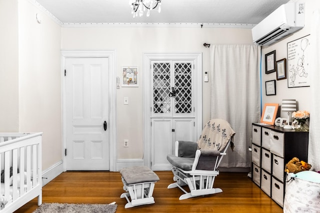bedroom featuring baseboards, wood finished floors, and a wall mounted air conditioner