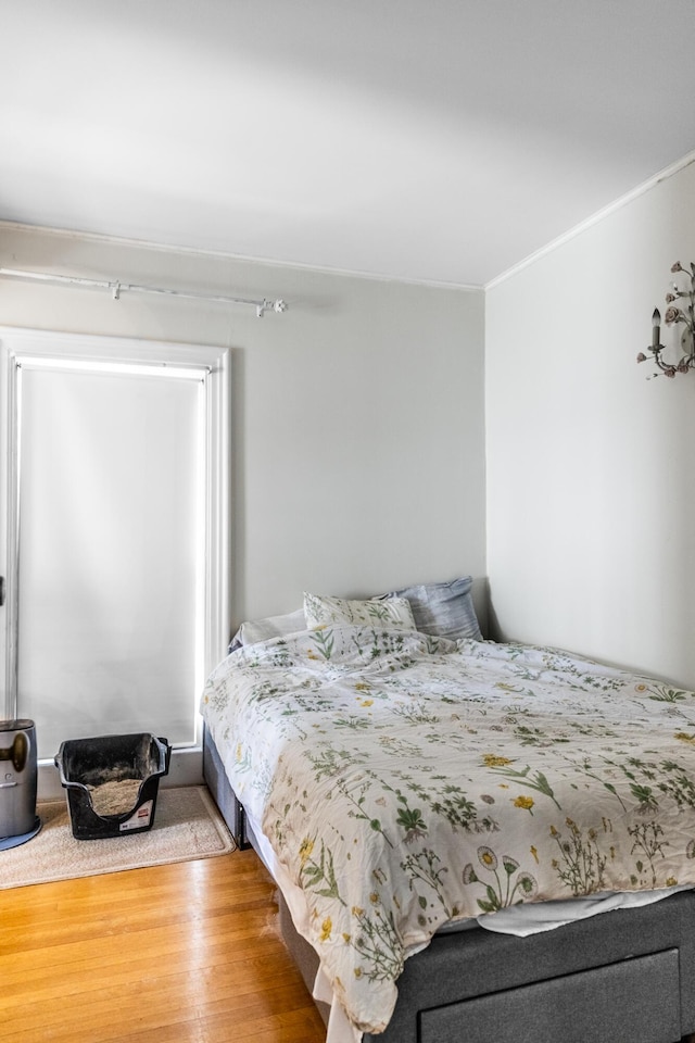 bedroom with wood finished floors and ornamental molding