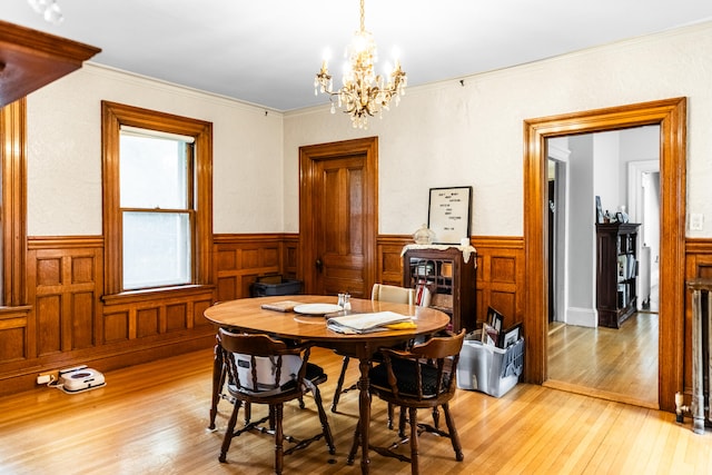 dining area featuring crown molding, light hardwood / wood-style flooring, and a chandelier