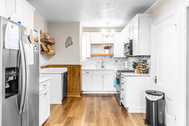 kitchen with stainless steel appliances, an inviting chandelier, open shelves, a sink, and light wood-style flooring