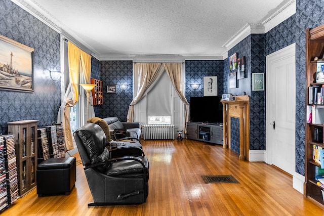 living room with a textured ceiling, crown molding, radiator, and hardwood / wood-style flooring