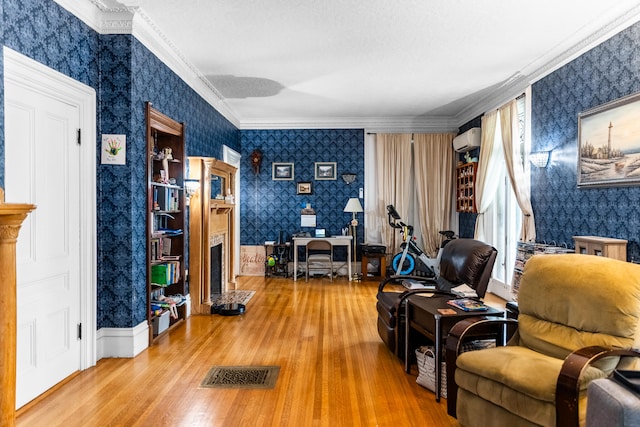 living area with light hardwood / wood-style flooring, ornamental molding, and a wall mounted air conditioner