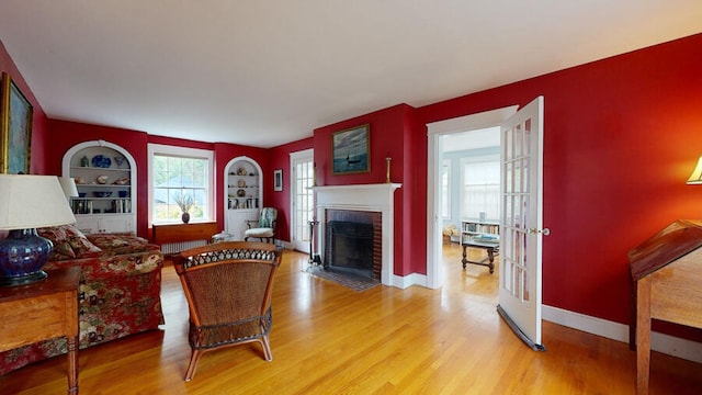 living room with hardwood / wood-style flooring, built in shelves, and a brick fireplace