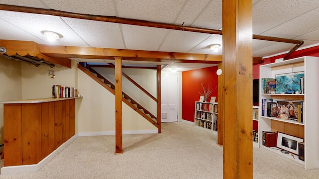 basement featuring light carpet and a drop ceiling