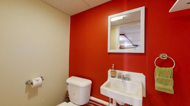 bathroom with a drop ceiling, toilet, and sink