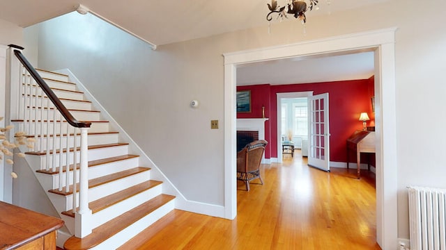 stairs with a fireplace, radiator, french doors, and hardwood / wood-style flooring