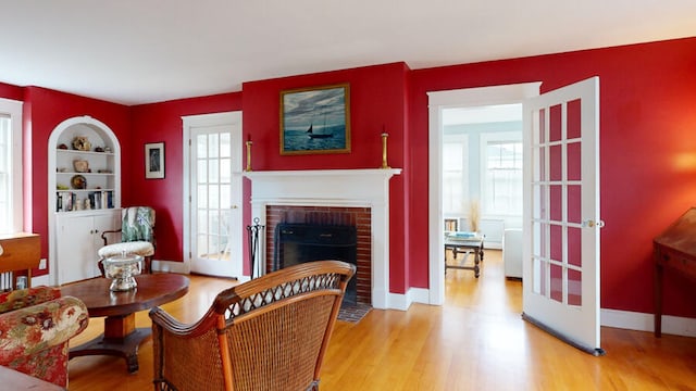 living room with built in shelves, a fireplace, and light hardwood / wood-style floors