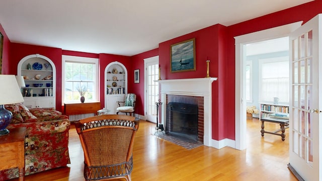 living room with built in shelves, hardwood / wood-style flooring, and a fireplace