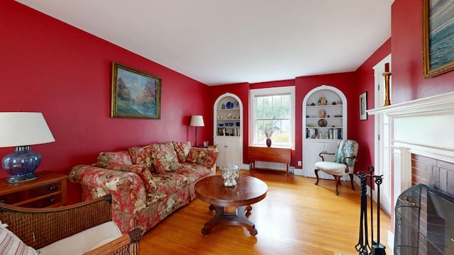 living room featuring radiator heating unit, a brick fireplace, and hardwood / wood-style floors