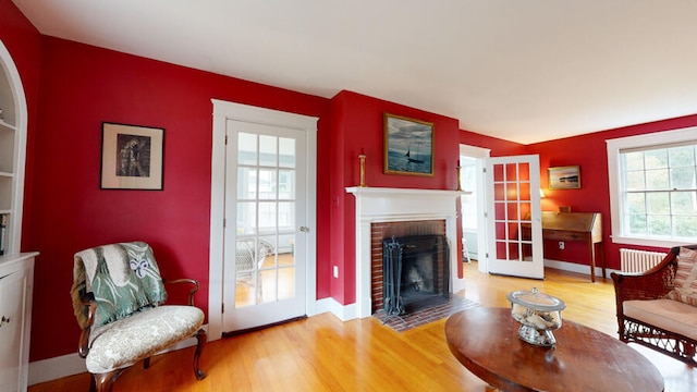 living room featuring a brick fireplace, radiator, and hardwood / wood-style floors