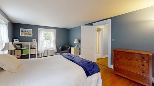 bedroom with light hardwood / wood-style flooring and radiator heating unit