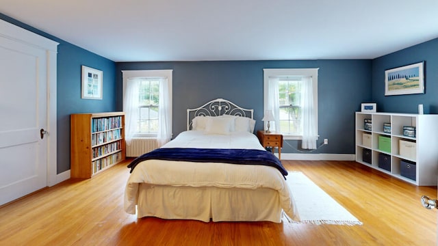 bedroom featuring light hardwood / wood-style flooring, radiator, and multiple windows