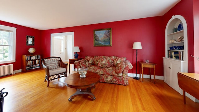 living room featuring radiator heating unit, wood-type flooring, and built in features