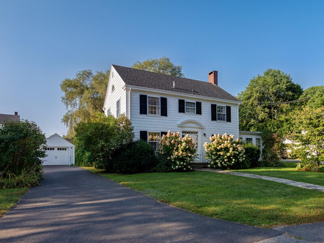 colonial inspired home with an outdoor structure, a garage, and a front lawn