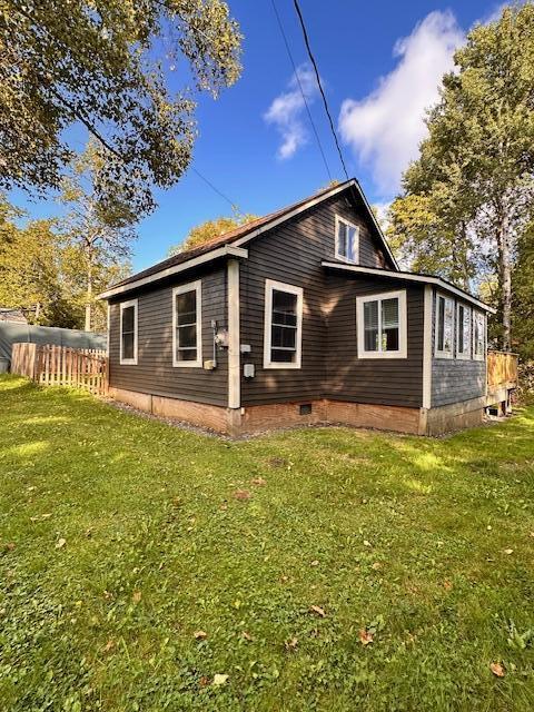 view of side of property with crawl space, fence, and a yard