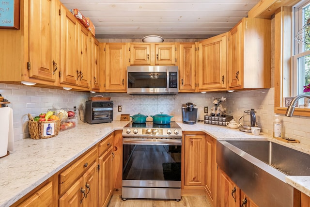 kitchen with decorative backsplash, light stone countertops, sink, and stainless steel appliances