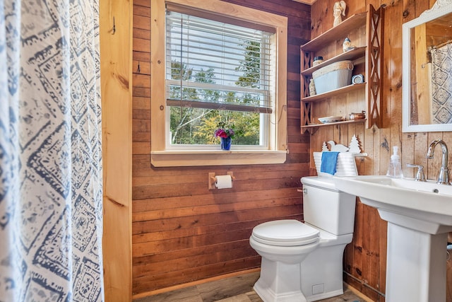 bathroom with hardwood / wood-style flooring, wood walls, toilet, and a wealth of natural light