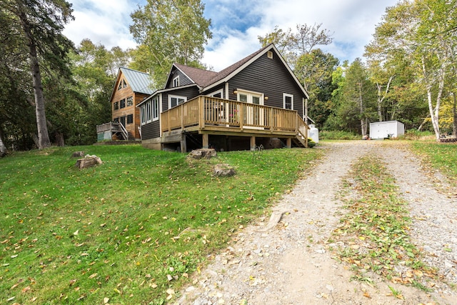 view of front of home with a deck, a storage unit, a front lawn, and a fire pit