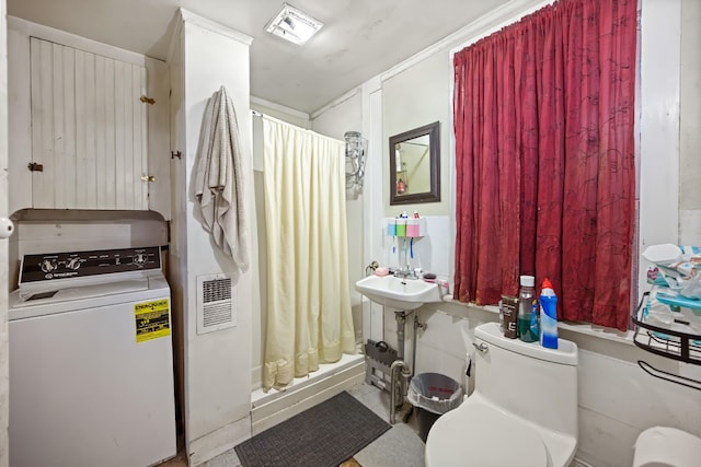 bathroom with washer / clothes dryer, toilet, and a shower with curtain