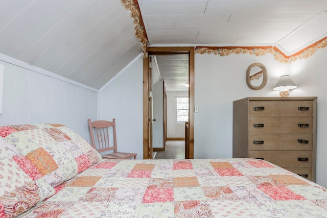 bedroom featuring lofted ceiling and wood walls