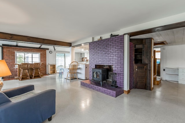 living room featuring bar, a wood stove, beamed ceiling, and brick wall