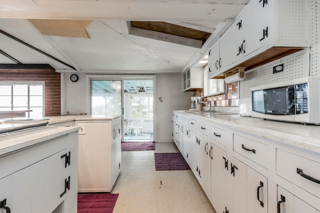 kitchen featuring white cabinetry, sink, and vaulted ceiling