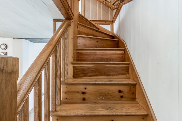 staircase featuring wood walls