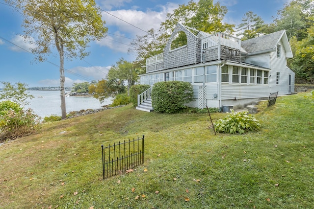 view of home's exterior with a lawn and a water view