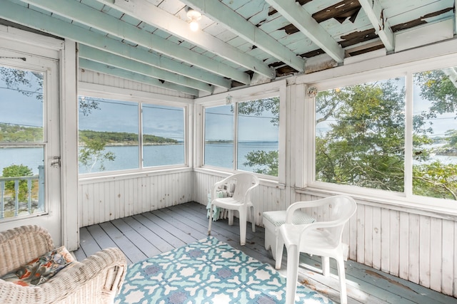 sunroom featuring a water view, beamed ceiling, and a wealth of natural light