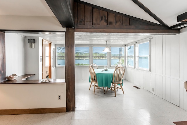 dining room with lofted ceiling, a water view, and wood walls