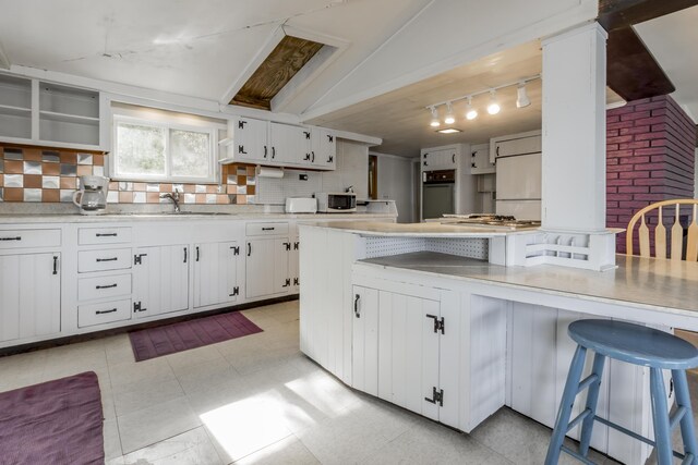 kitchen featuring a breakfast bar area, refrigerator, white cabinets, and oven