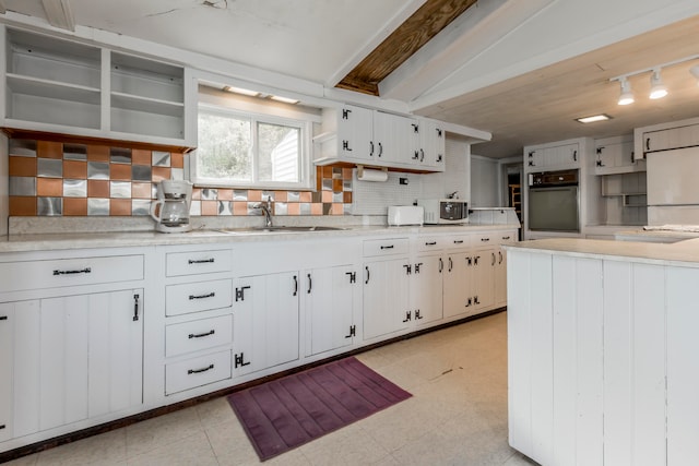 kitchen featuring tasteful backsplash, oven, sink, white cabinetry, and white refrigerator