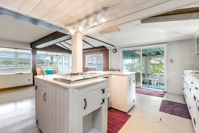 kitchen with lofted ceiling, track lighting, wood ceiling, a center island, and white cabinets