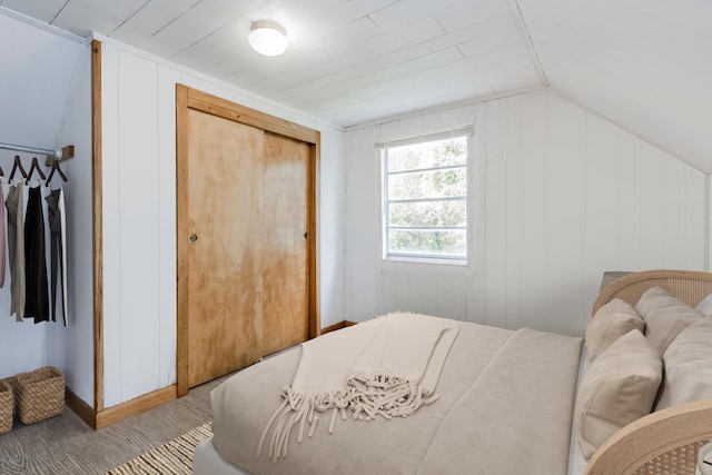 bedroom featuring a closet, wood walls, wooden ceiling, and vaulted ceiling