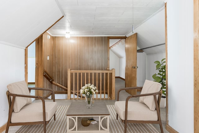 living area with vaulted ceiling and wooden walls