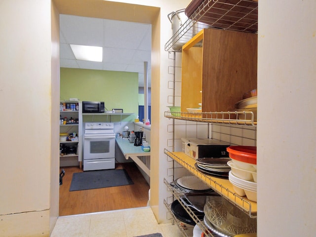 interior space with electric range, light wood-type flooring, and a drop ceiling